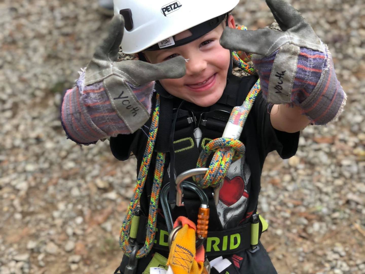 a little boy wearing a helmet riding a motorcycle down a dirt road