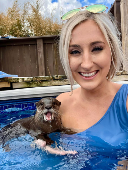 a woman holding a dog posing for the camera